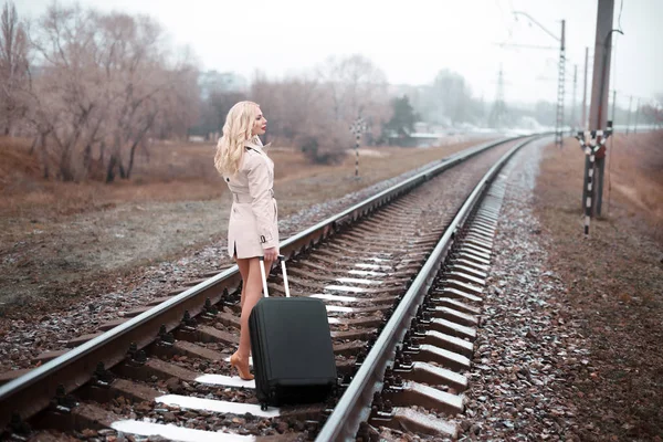 Visão traseira da mulher com bagagem andando na estrada ferroviária — Fotografia de Stock