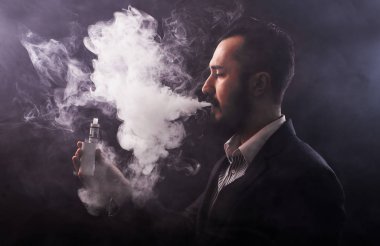 Bir gelişmiş kişisel Buharlaştırıcı veya e-sigara kullanarak dostum, kapat; koyu tonlu görüntü.