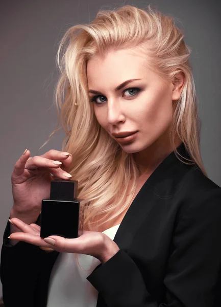 Een blond meisje met fles parfum in handen — Stockfoto