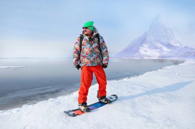 Parlak spor giyim güzel dağlar karşı denge hile yaparak Snowboarder