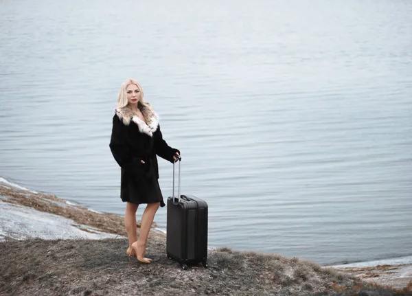 Mujer joven en abrigo de piel llevando equipaje — Foto de Stock
