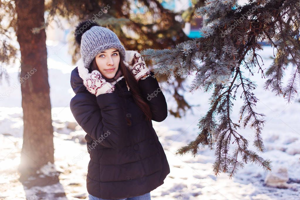 Christmas girl outdoor portrait. Sunny day. Beauty young woman Having Fun in Winter Park. Good mood, knitted hat and mittens