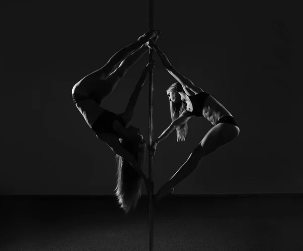 Dua wanita muda seksi latihan tiang tari dengan latar belakang gelap. Foto hitam dan putih — Stok Foto