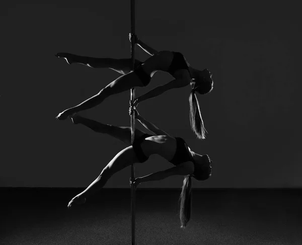 Dois jovens dançarinos flexíveis fazendo truques acrobáticos difíceis com um pólo. preto e branco — Fotografia de Stock