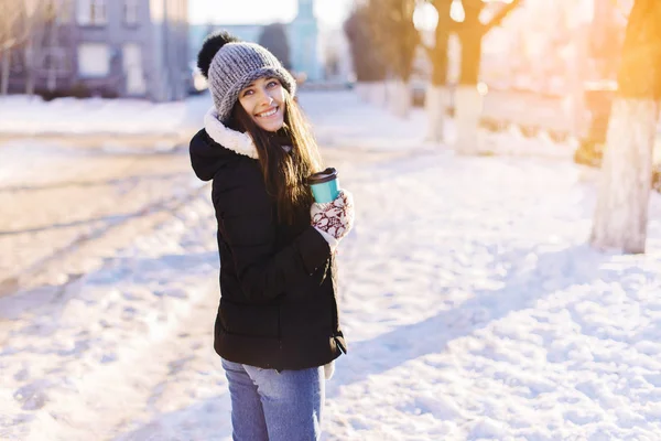 若くてきれいな女性が冬の通り背景に屋外のコーヒーを飲む. — ストック写真