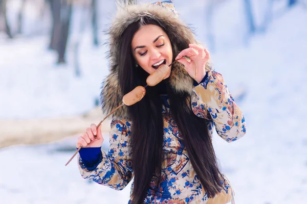 若い女性冬の屋外のソーセージを食べる — ストック写真