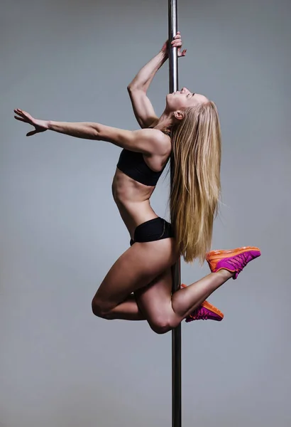Genç seksi kadın egzersiz pole dance gri bir arka plan — Stok fotoğraf
