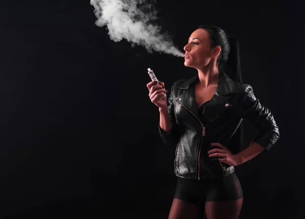 Jeune femme fumant cigarette électronique sur fond noir — Photo