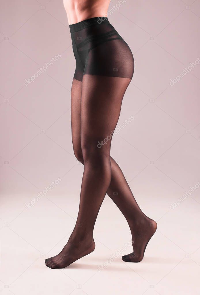 Female legs in black pantyhose on gray background