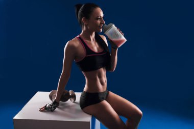 Proteinler üzerinde mavi arka plan içme çekici genç kadın