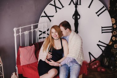 Ebeveynler büyük saatin yanında onun yeni doğan bebek bekleyen 