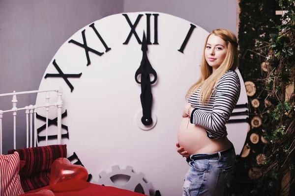 Беременная женщина около больших часов — стоковое фото