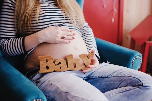 Embarazada chica es celebración de madera cartas bebé —  Fotos de Stock