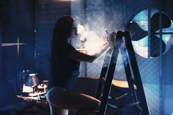 seksi genç kadın kanepe vaping e-sigara karşı koyu mavi ba