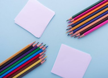 Anımsatıcı yapışkan notlar ve renkli kalemler üzerinde pastel mavi izole