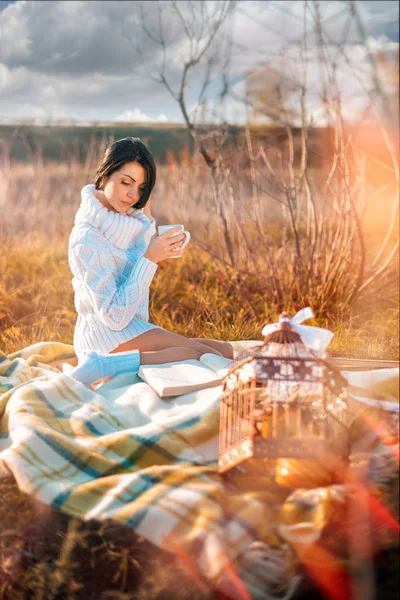 Menina bonita vestindo camisola de malha branca encontra-se em xadrez e lê o livro no outono — Fotografia de Stock