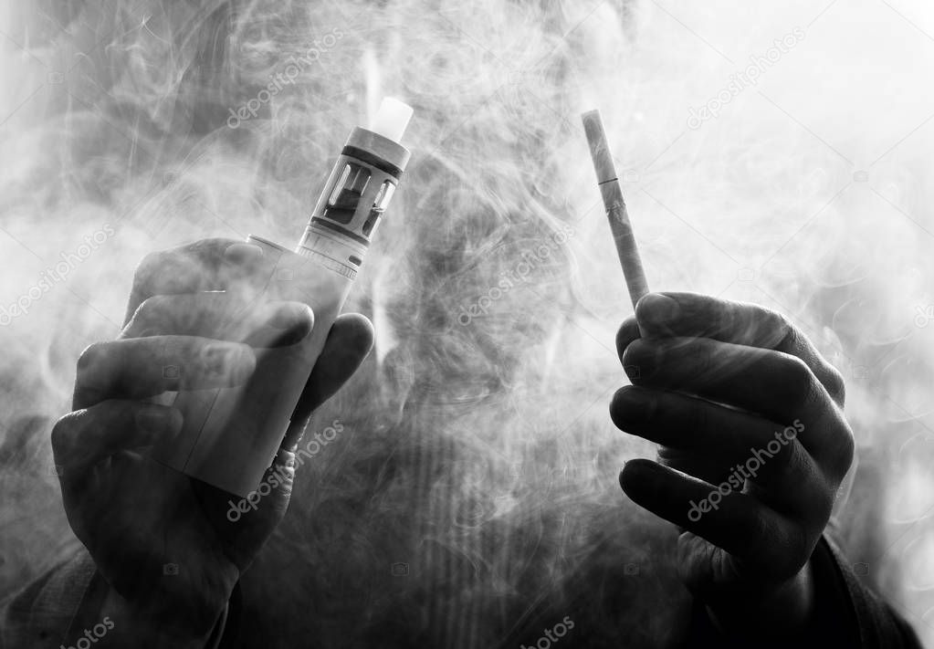 vaping man holding a mod and cigarette. A cloud of vapor.