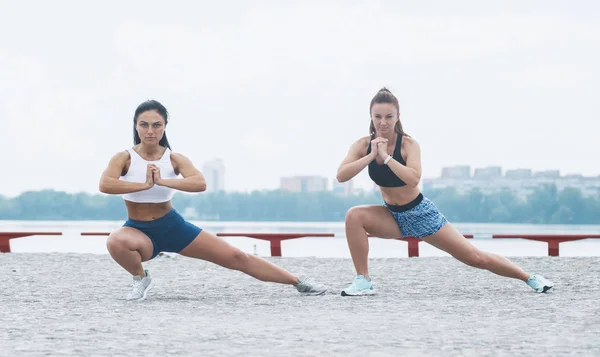 两个有吸引力的女性在海边。锻炼后拉伸腿 — 图库照片