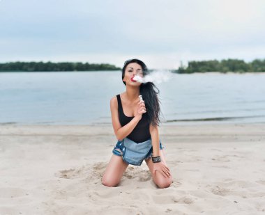 Seksi kadın vaping elektronik nargile sahilde. Vape kavramı