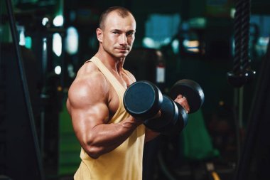 Güçlü atletik erkekler vücut geliştirme konusunda kas geliştiriyorlar. Kaslı vücut geliştirici yakışıklı erkekler spor salonunda çıplak gövde egzersizleri yapıyor.