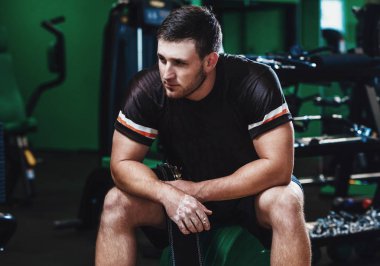 Fitness salonunda bankta oturan kaslı bir adam portresi