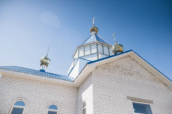 Eastern orthodox crosses on gold domes (cupolas) againts blue sky with clouds