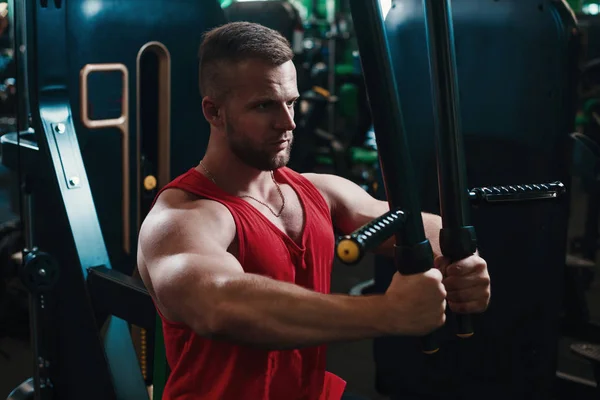 Man training hard at fitness gym. Man doing workout on fitness machine at gym. Gym trainer athlete working out chest muscles doing strength training exercises on gym benchpress equipment.