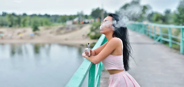 Ατμίσματος. Νεαρή όμορφη γυναίκα (vaping) ε-τσιγάρο με καπνό σε εξωτερικούς χώρους το κάπνισμα. Ατμός έννοια. — Φωτογραφία Αρχείου