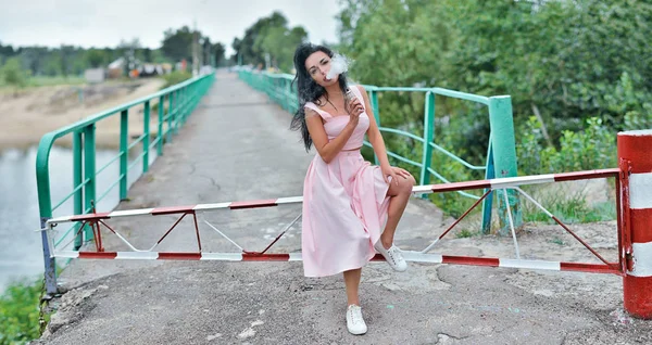 Mulher bonita fumar (vaping) e-cigarro com fumaça ao ar livre. Conceito de vacilação . — Fotografia de Stock