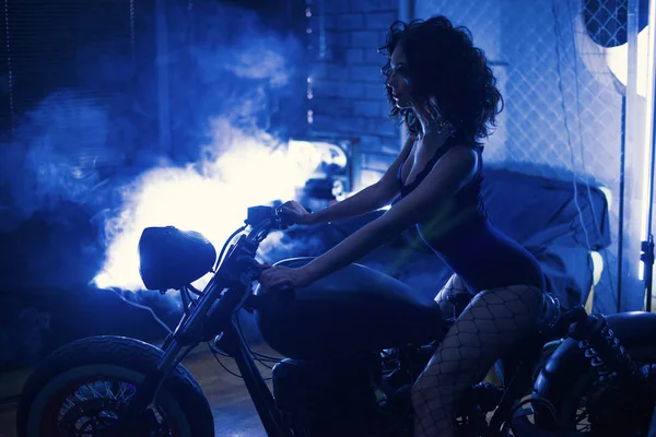En bicicleta. Chica sexy con el cuerpo perfecto sentado en la motocicleta. Color azul profundo — Foto de Stock