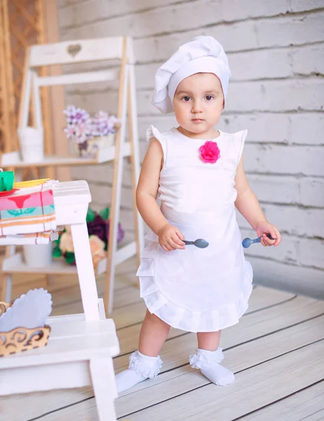 Petite fille en chapeau de cuisinier et tablier dans la cuisine à la maison — Photo