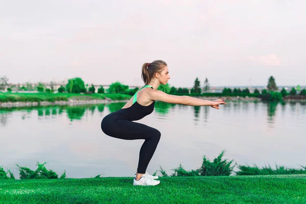 Bir atlet kadının yapması portresi göl kenarında çimenlerin üzerinde açık havada ağız kavgası.