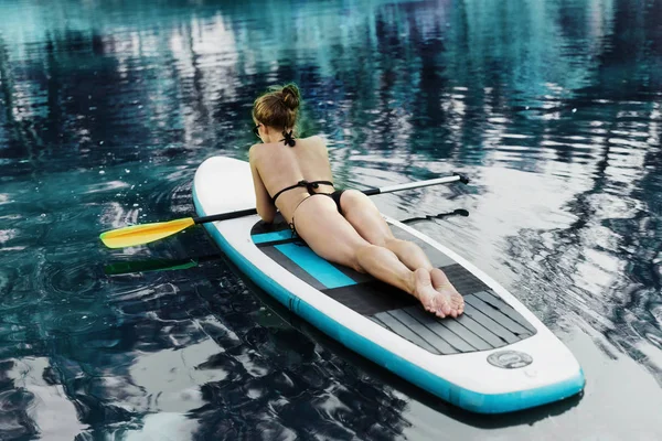 Sexy beautiful woman relaxing on a SUP board. Back view. The girl sunbathes — Stock Photo, Image
