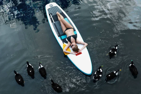 Woman relaxing on a SUP board on lake. The girl swimming near ducks — Stock Photo, Image