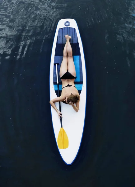 Attraktive Frau im Bikini sonnt sich auf einem Surfbrett, Luftaufnahme — Stockfoto