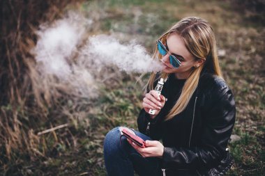 Vaping. Genç güzel kadın (vaping) e-sigara duman açık havada ile. Buharı kavramı.