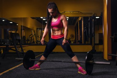 Erkek Deadlift egzersiz kilo bar ile gerçekleştirme. Kendine güvenen genç kadının spor salonunda ağırlık kaldırma egzersiz yapması.