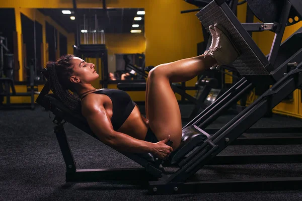 व्यायामशाळा मध्ये पाय प्रेस करत एक फिट तरुण स्त्री साइड दृश्य . — स्टॉक फोटो, इमेज