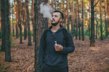 Model vaper vaping bir Buharlaştırıcı açık havada. Güvenli yasaktır. Genç vaper.