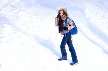 Kış sporu aktivitesi. Sırt çantası ve kar ayakkabılarıyla yürüyüş yapan kadın gün batımında Quebec, Kanada 'da kar yolu ormanlarında kar ayakkabısı giyiyor. Kozalaklı ağaçlar ve beyaz karla güzel bir manzara..
