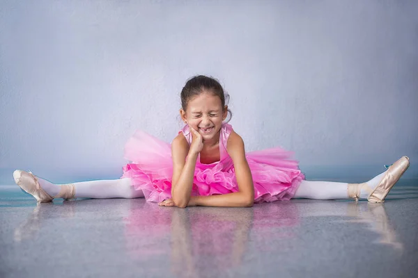 Junge Ballerina in pinkfarbenen Kleidern sitzt während des Tanzkurses auf dem Boden. — Stockfoto