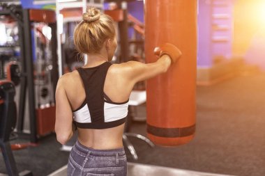 Çekici kadın Delme A çanta ile boks eldiven içinde jimnastik salonu. Arkadan Görünüm