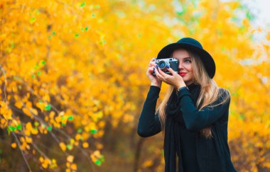 genç kadın açık havada sonbaharda fotoğraf çekme. Sarı yapraklar arka plan