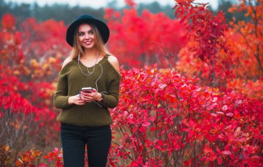 Mutlu kız siyah şapka dans ve sonbaharda doğa üzerinde müzik dinlemek