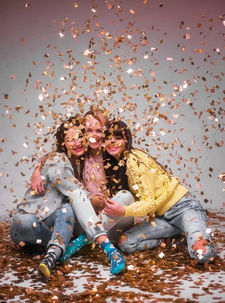 Tres hermosas chicas jóvenes divirtiéndose en la fiesta de Año Nuevo en confeti —  Fotos de Stock