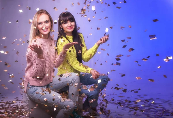 Dos hermosas chicas jóvenes divirtiéndose en la fiesta de Año Nuevo en confeti —  Fotos de Stock
