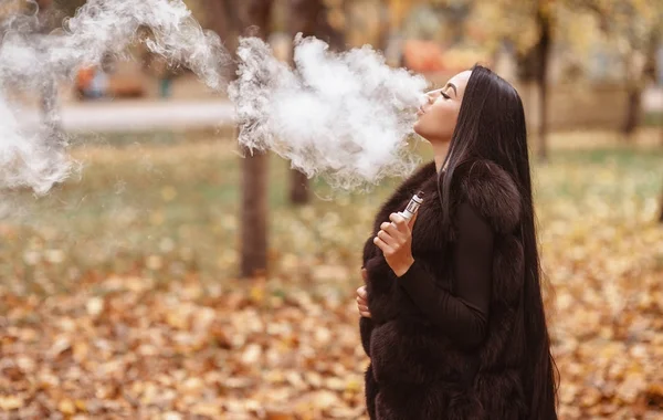 Vapeado. Joven hermosa mujer vapeando con humo al aire libre. Concepto de vapor . — Foto de Stock