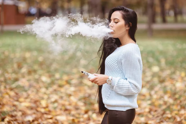 Vaping. Fiatal gyönyörű nő vaping a füst a szabadban. Vapor koncepció. — Stock Fotó