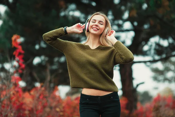 Joven hipster elegante hermosa chica escuchando música, teléfono móvil, auriculares, disfrutando, traje de mezclilla, sonriendo, feliz, accesorios frescos, estilo vintage, divirtiéndose, riendo, parque —  Fotos de Stock