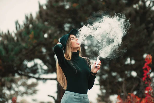 Bastante joven hipster mujer en negro sombrero vape ecig, dispositivo de vapeo . — Foto de Stock